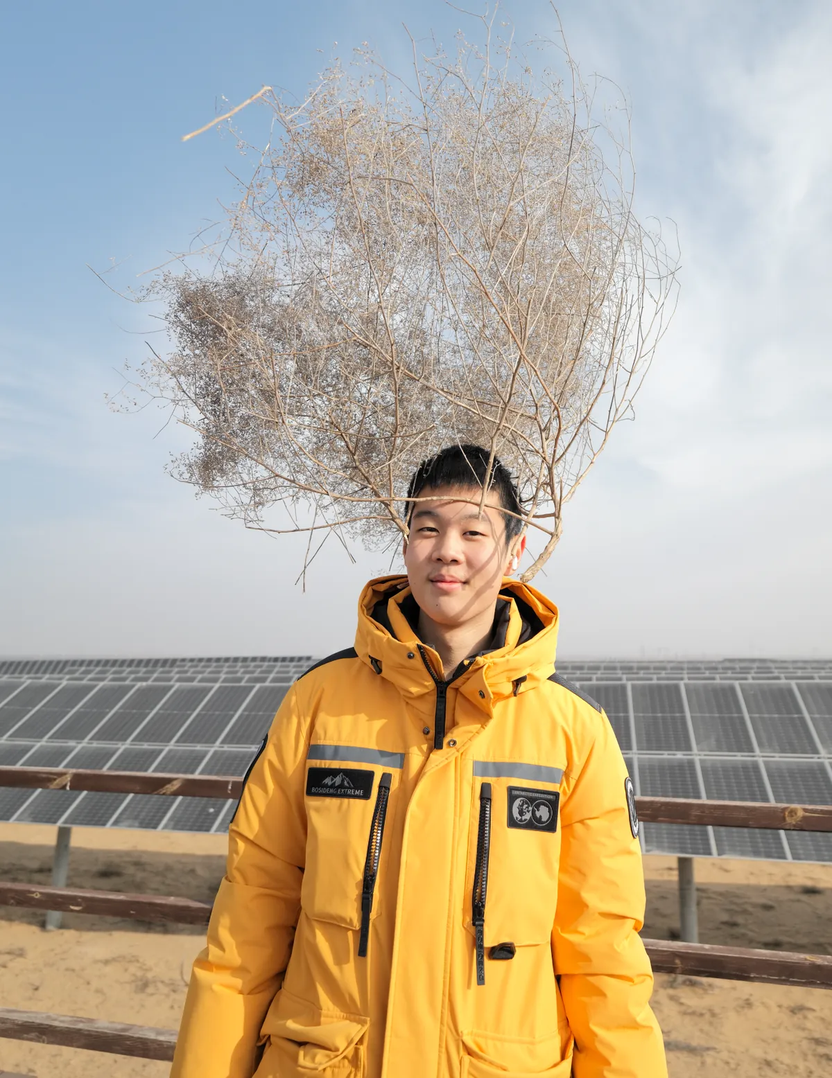 Guowei Wang at a solar farm in the desert, wearing a yellow expedition jacket